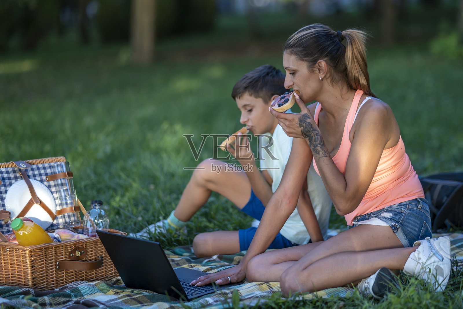 一位年轻的母亲和她的儿子在公园里野餐，玩得很开心。照片摄影图片
