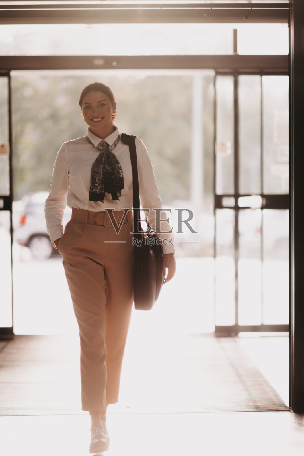 被授权的拉丁女商人在现代办公室自信地大步迈进。照片摄影图片