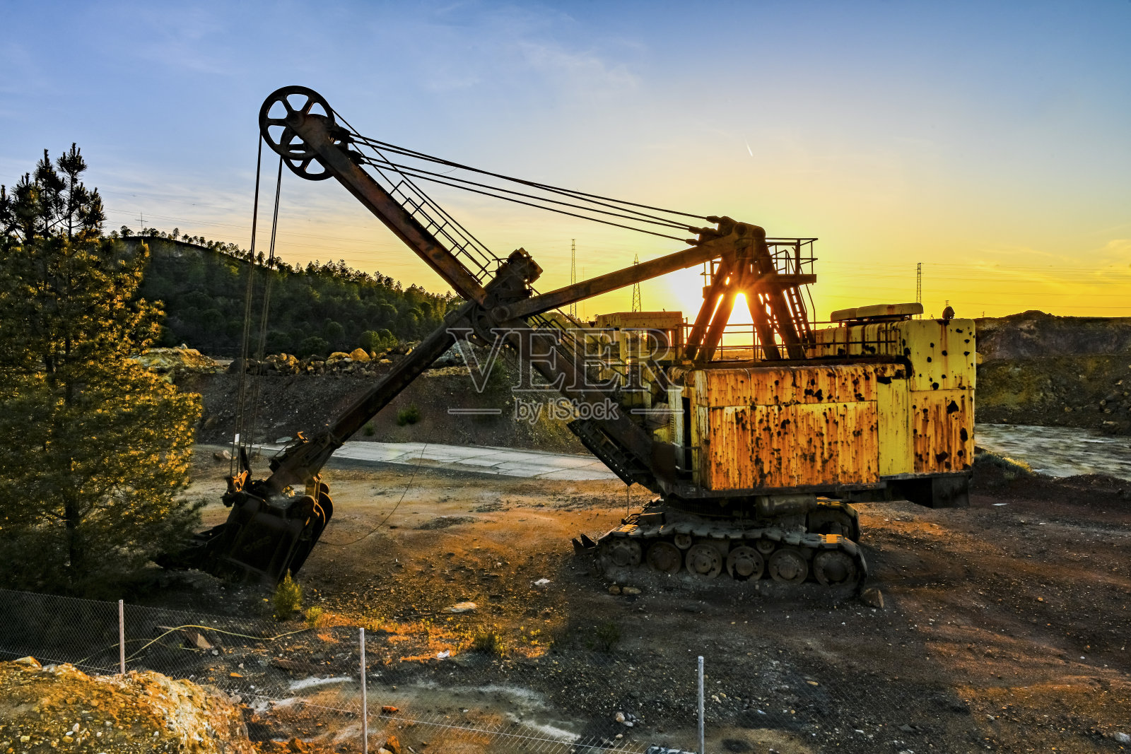 在采石场废弃的采矿挖掘机上的日落照片摄影图片