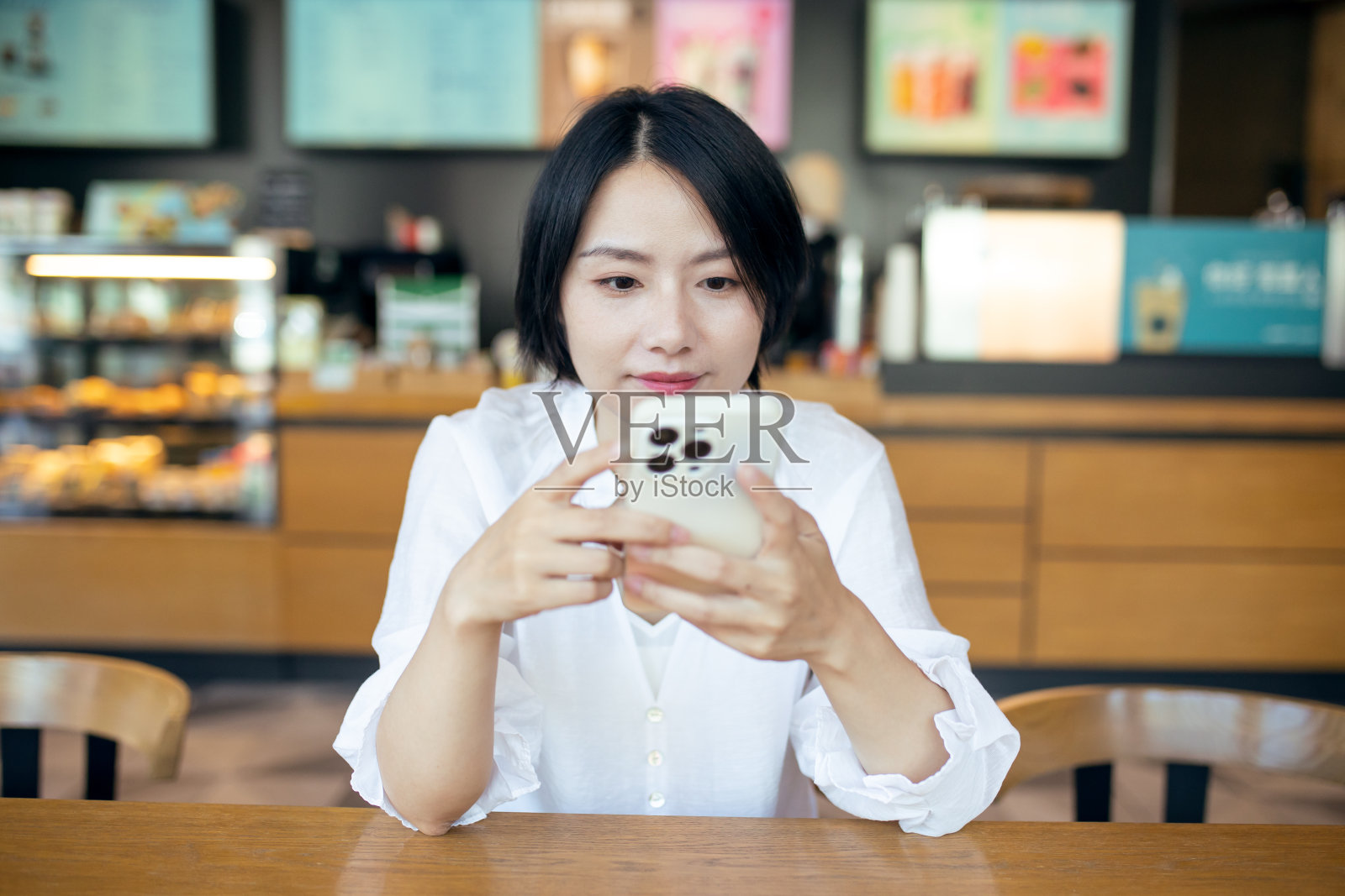 在咖啡店用手机的女人。照片摄影图片