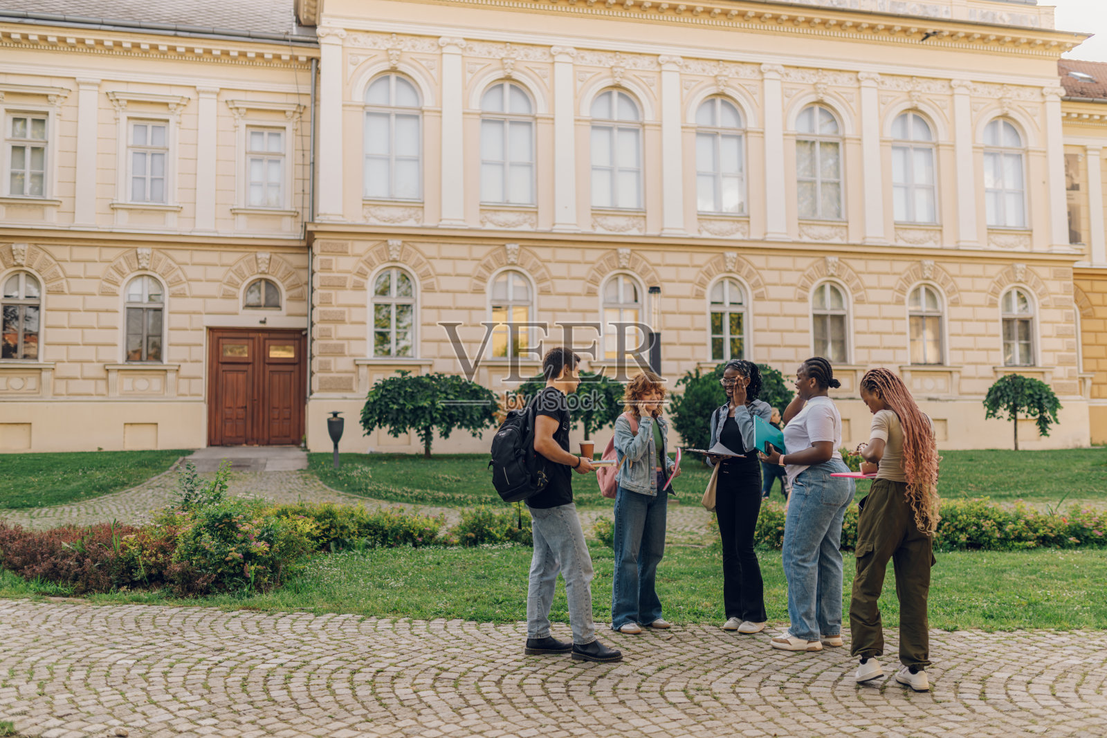 各种各样的学生拿着课本站在校园里的全身像照片摄影图片