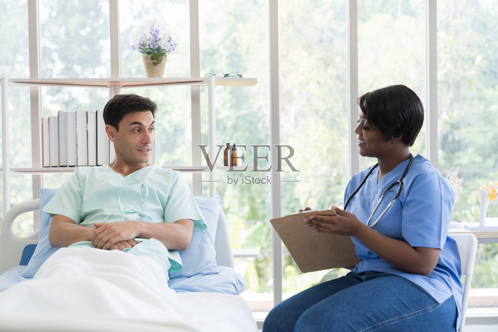 护士在医院病房的床上照顾男病人。女助理在诊所检查男病人照片摄影图片