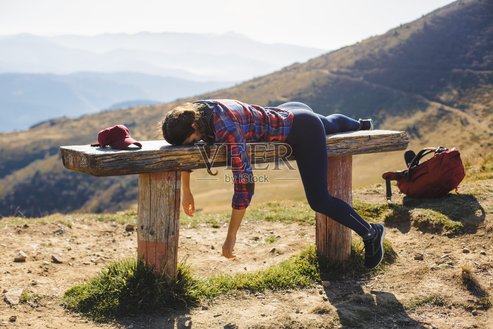 疲惫的徒步旅行者躺在山景中的木凳上照片摄影图片