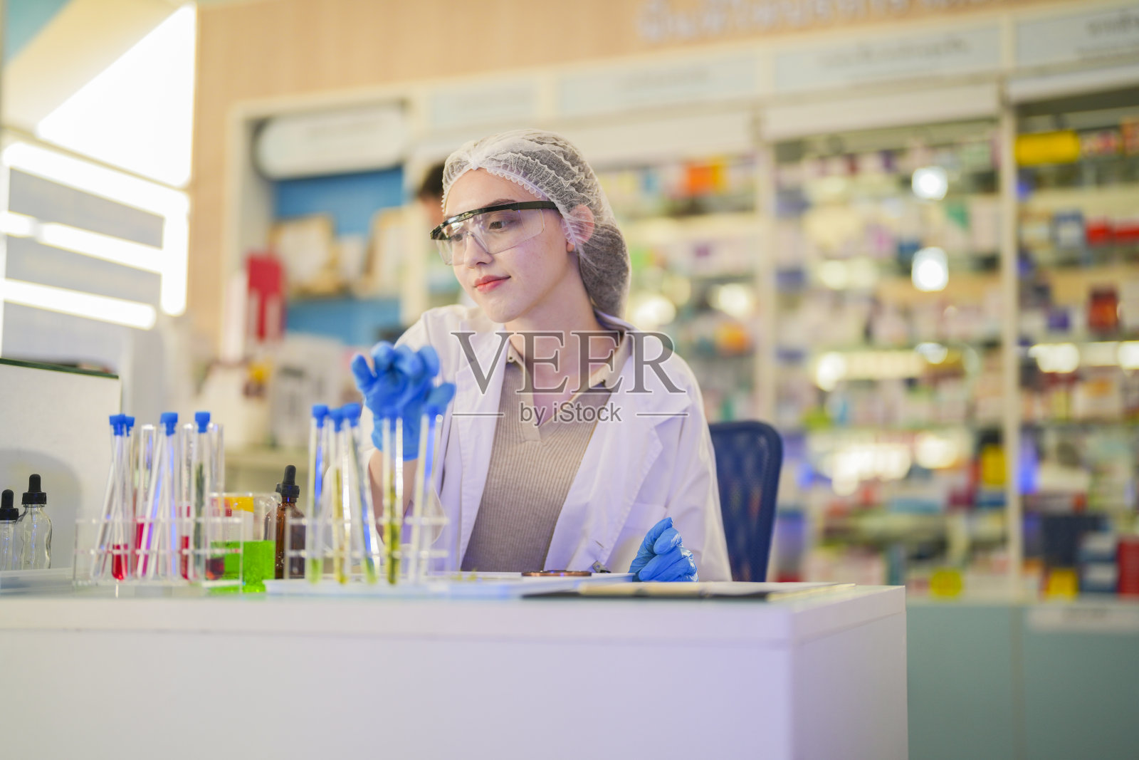 女科学家通过试管进行化学液体和植物样本的实验。在一个实验室里，在一个现代化的实验室里，通过安全、干净的测试，把测试样本放在后台。照片摄影图片