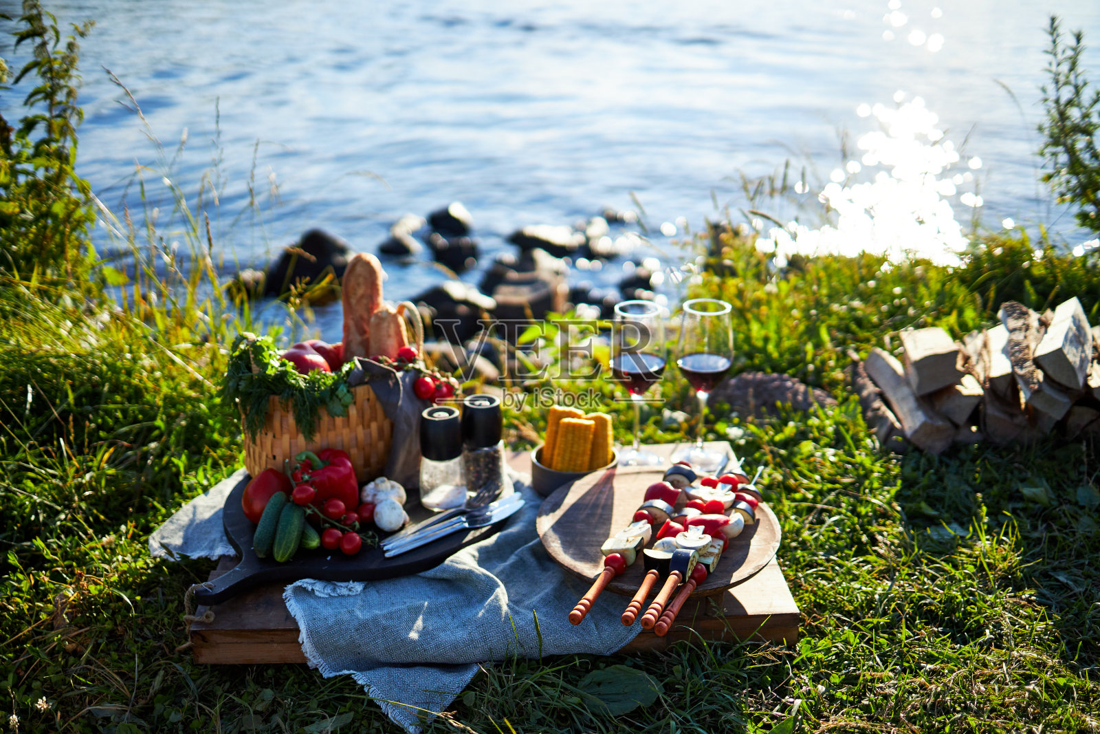 夏日在河边野餐，用木托盘盛上蔬菜、烤肉串和红酒照片摄影图片