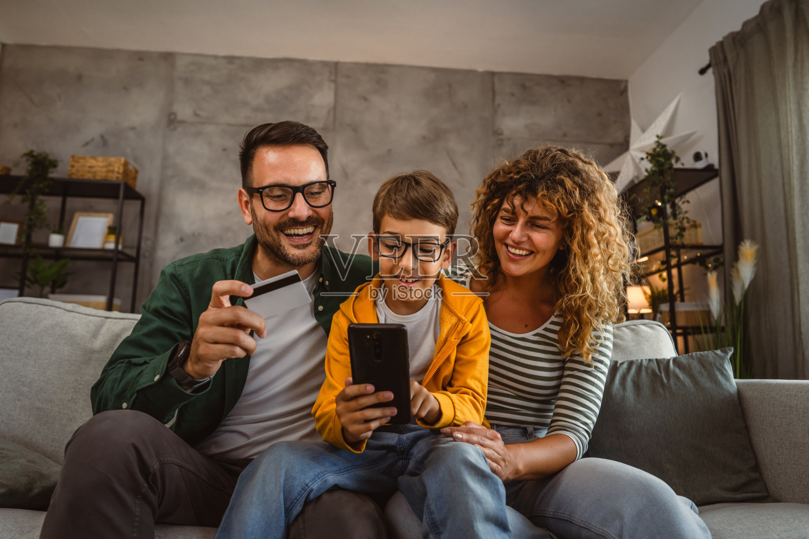 妈妈、爸爸和儿子用信用卡在手机上网购照片摄影图片