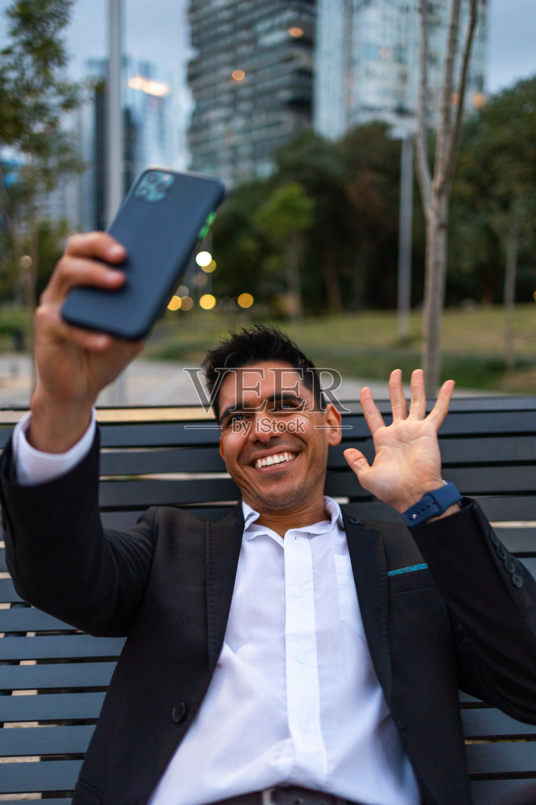 年轻快乐的拉丁商人坐在办公大楼外进行视频通话照片摄影图片