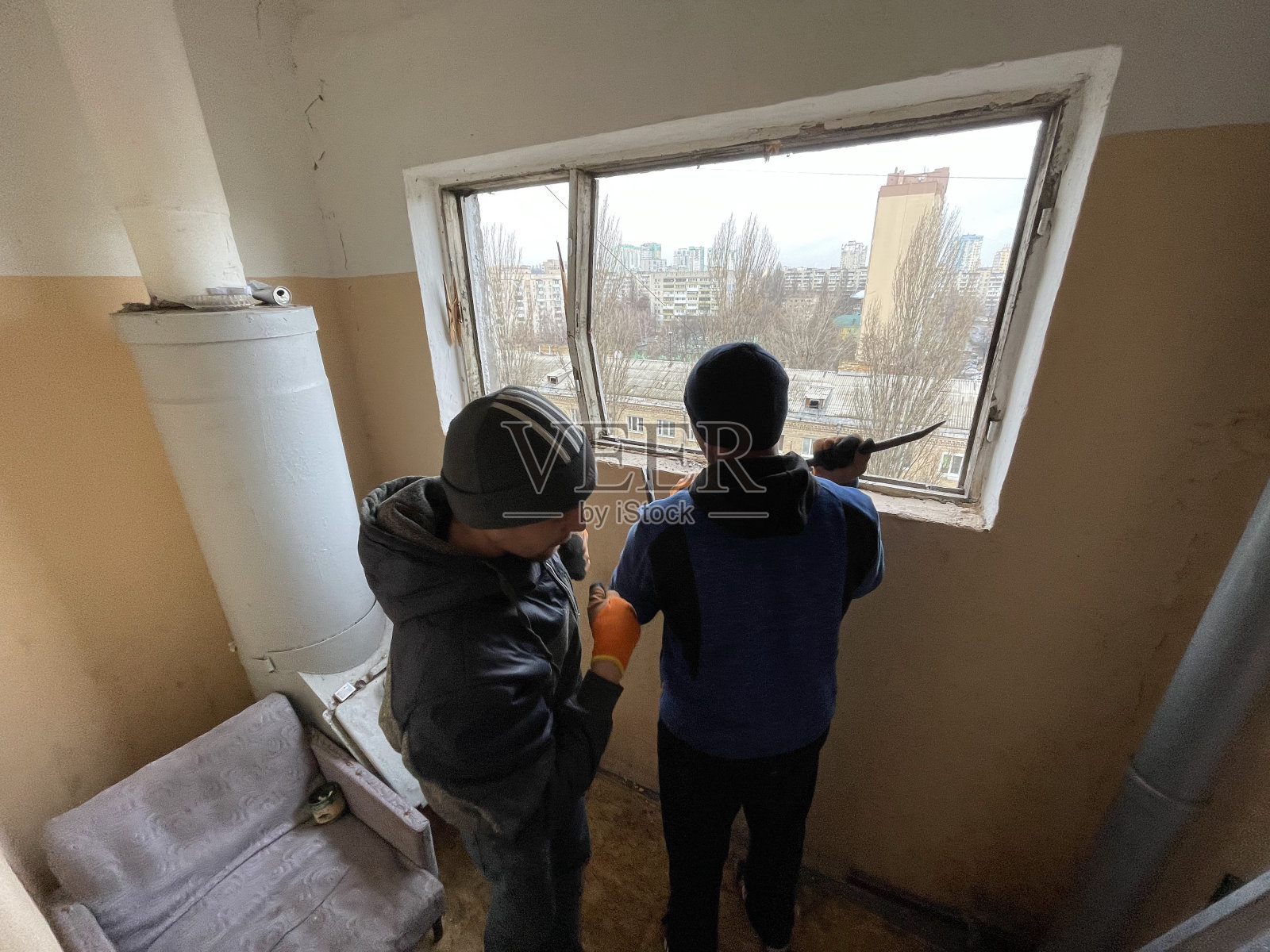 在公寓大楼的入口处安装新的玻璃窗。一名工人在一栋高层住宅楼里进行维修照片摄影图片