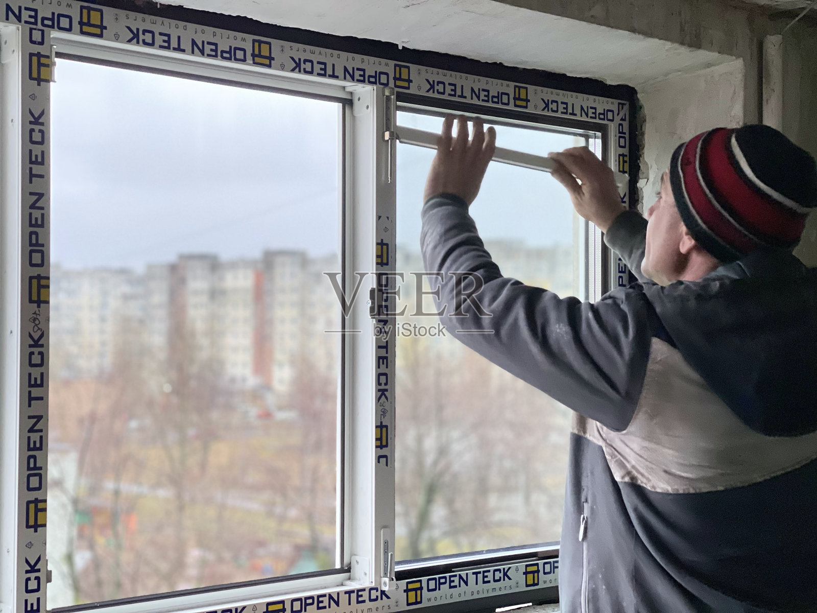 在公寓大楼的入口处安装新的玻璃窗。一名工人在一栋高层住宅楼里进行维修照片摄影图片