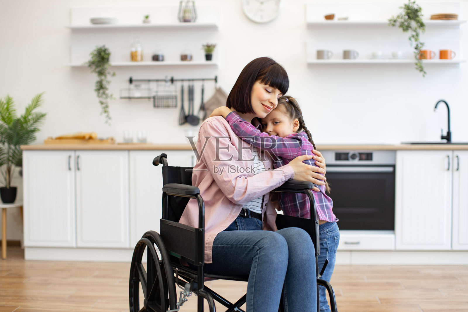 坐在轮椅上的慈母在厨房里拥抱女儿照片摄影图片