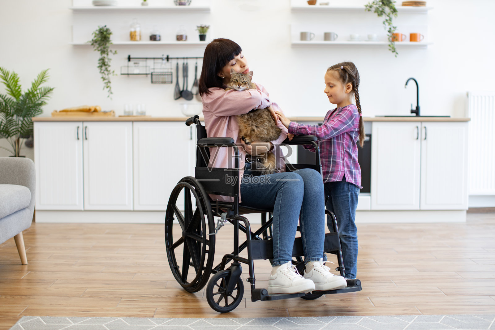 坐在轮椅上的妇女带着女儿在室内照顾宠物猫照片摄影图片