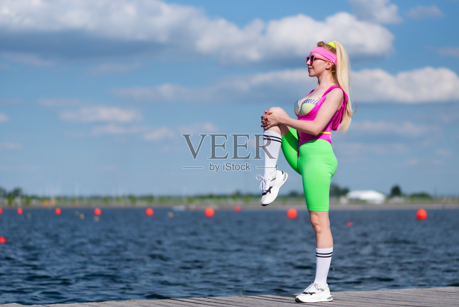 年轻美丽的金发女子穿着运动短裤，粉红色的紧身衣和粉红色的太阳镜在户外做运动。穿着运动服做运动。运动，积极的生活方式，运动训练，健康的生活方式照片摄影图片