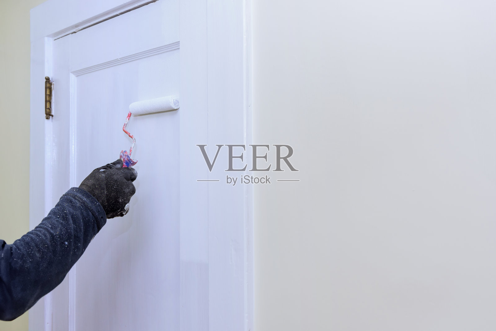 门在维修时用滚轮涂上白色油漆照片摄影图片