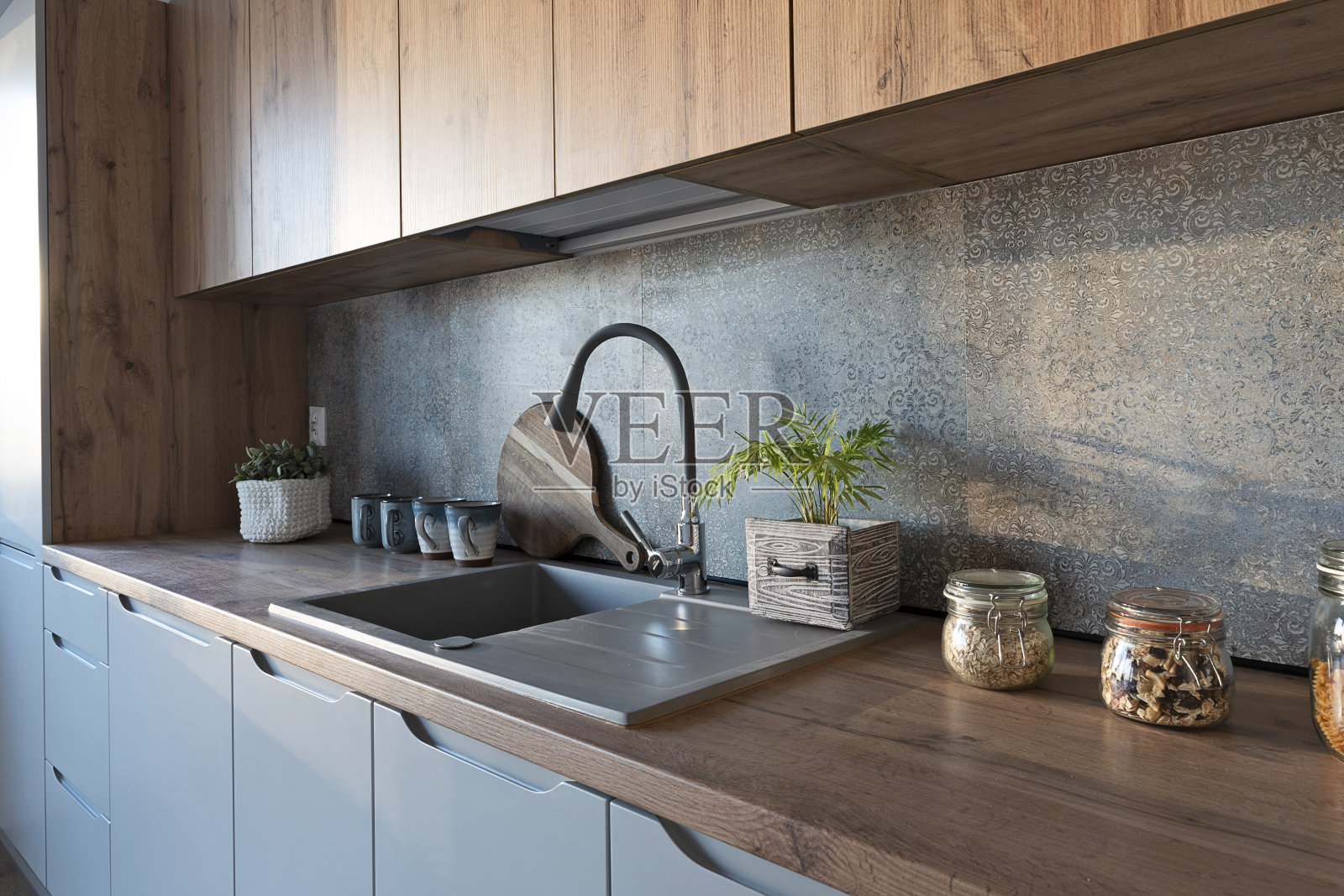 餐厅内的现代厨房，配有木制台面，厨房水槽和墙上的图案瓷砖。家居装饰。照片摄影图片