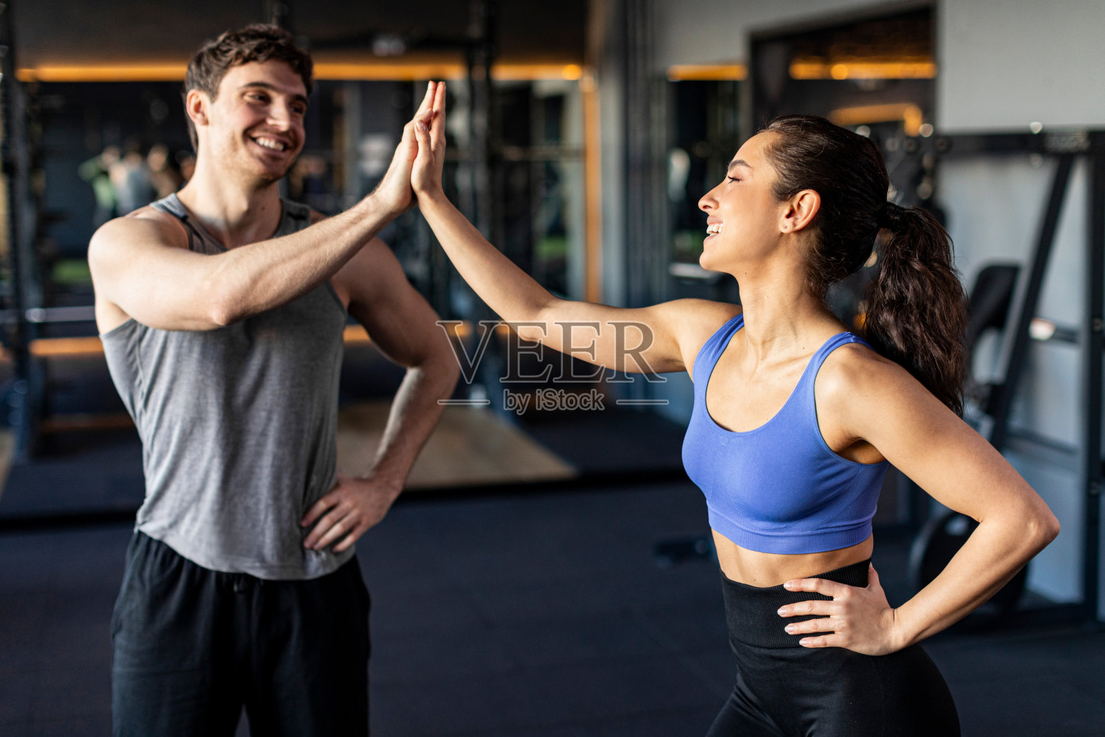 运动健身女士和男教练在漆黑的健身室内训练时互相击掌，面带微笑照片摄影图片