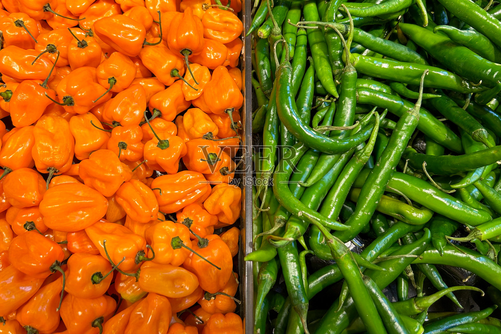 左边是一堆亮橙色的哈瓦那辣椒，右边是一堆绿色的塞拉诺辣椒照片摄影图片