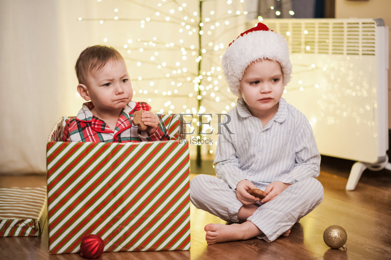 蹒跚学步的哥哥和妹妹穿着圣诞睡衣，在家里拿着大大的新年礼物照片摄影图片