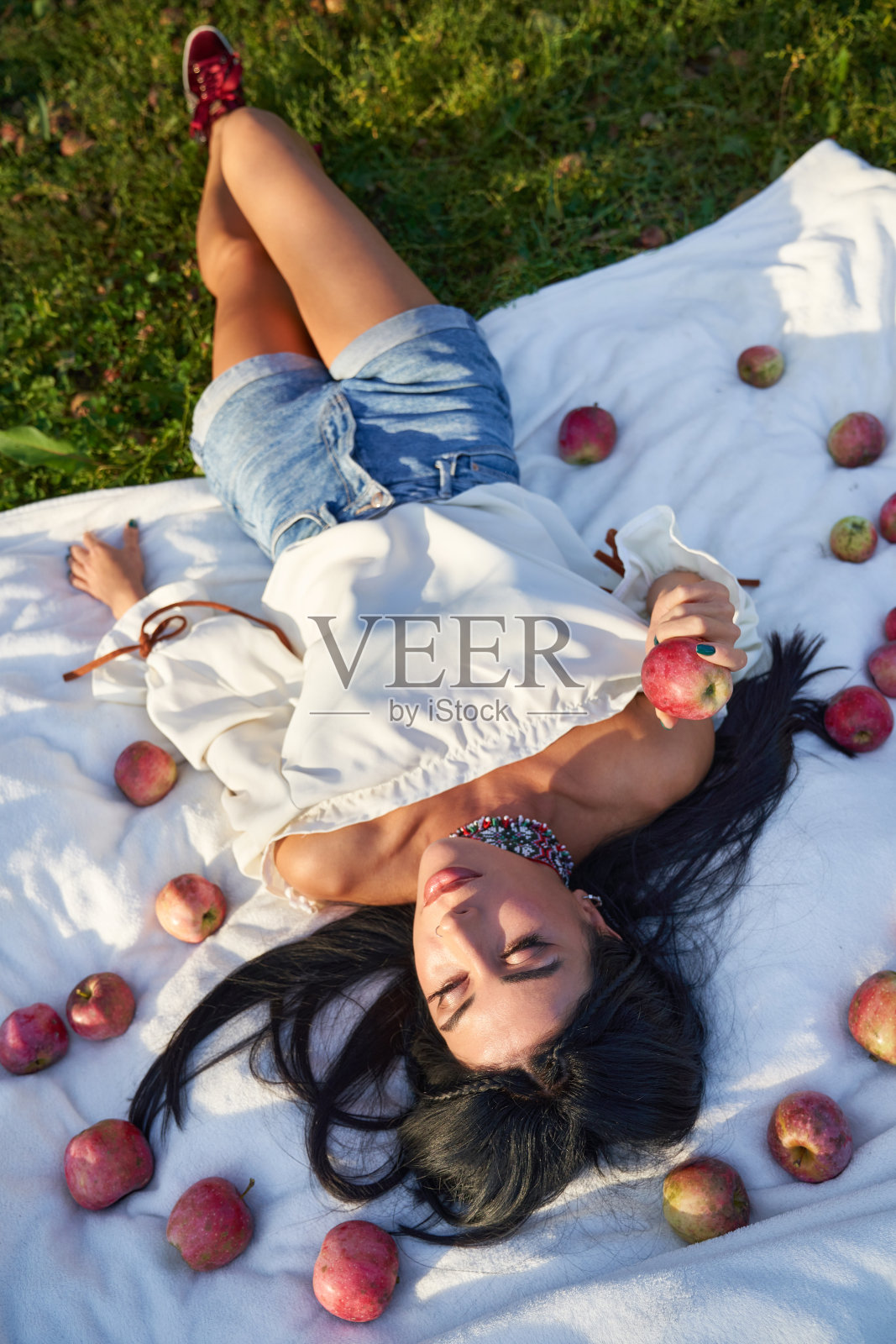 草地上有苹果的美女。照片摄影图片
