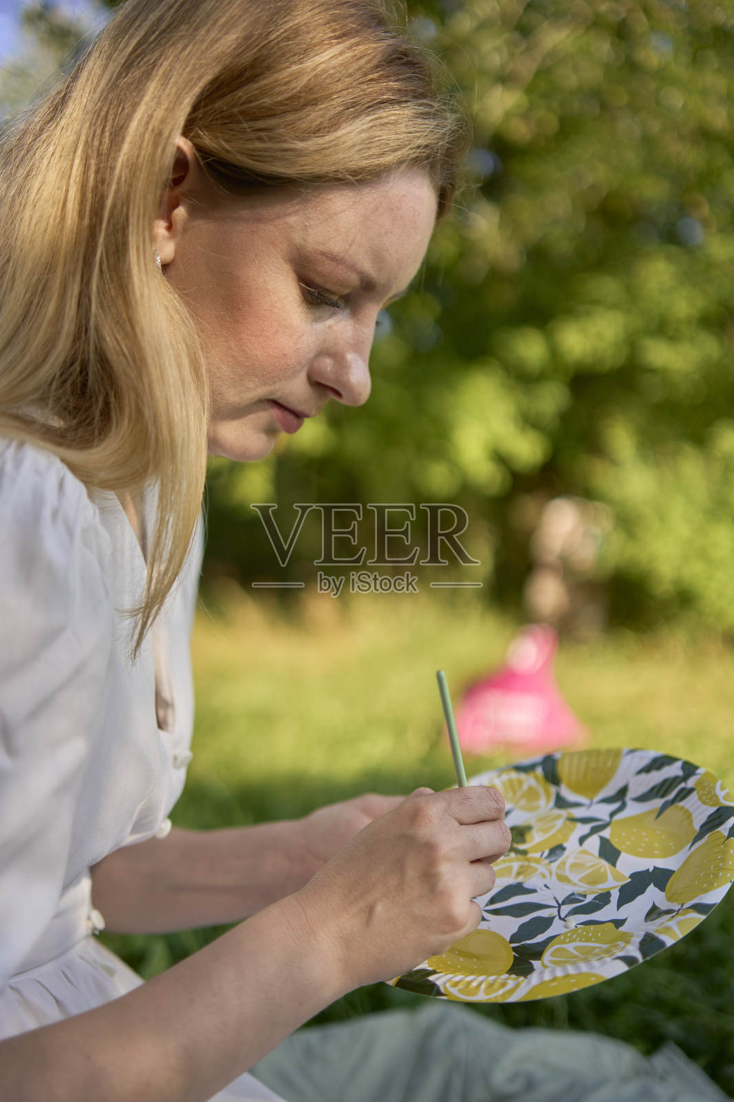 一位穿着白色连衣裙的年轻漂亮的画家在河岸上画画照片摄影图片