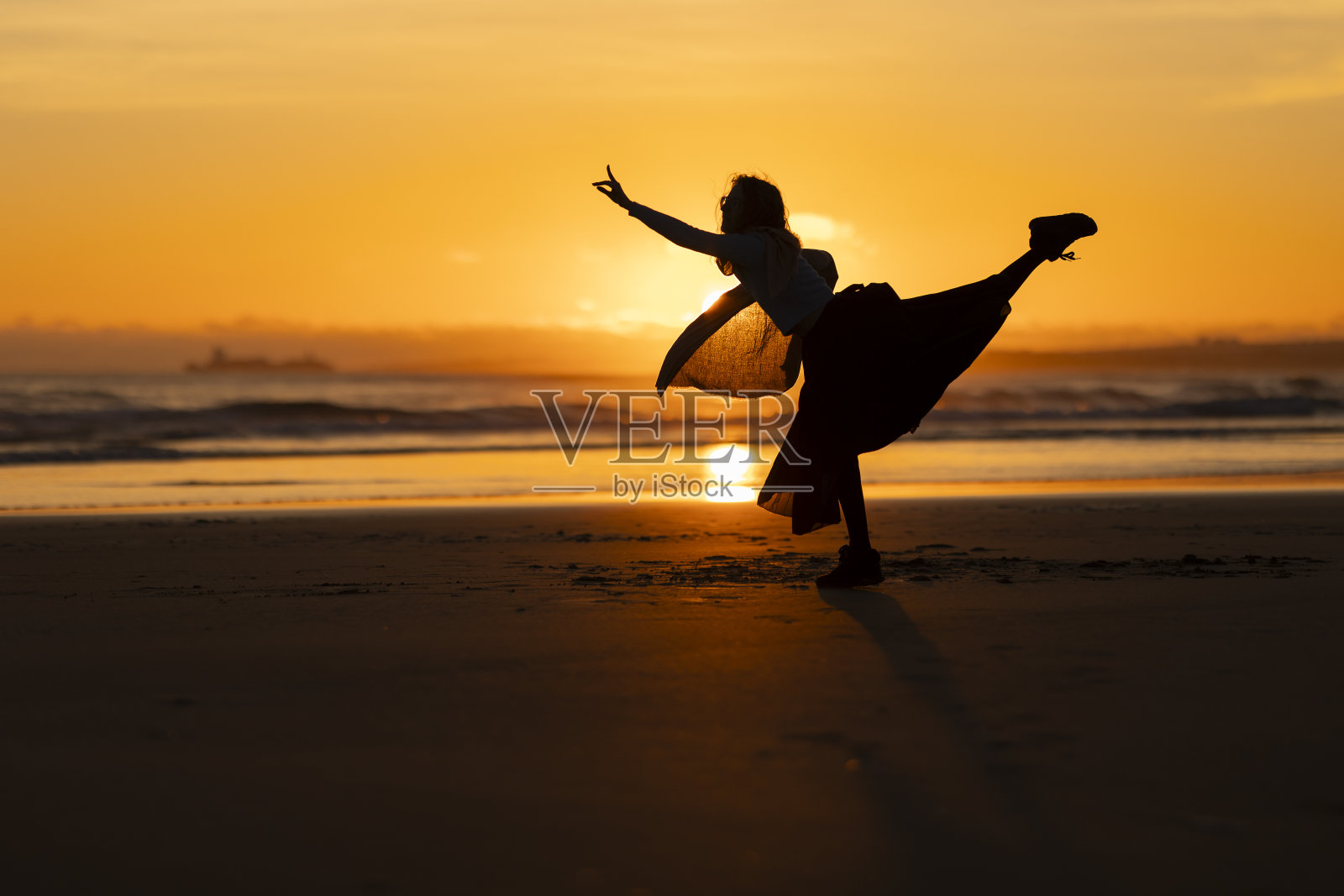 日落时分，一个女人在海滩上跳舞照片摄影图片
