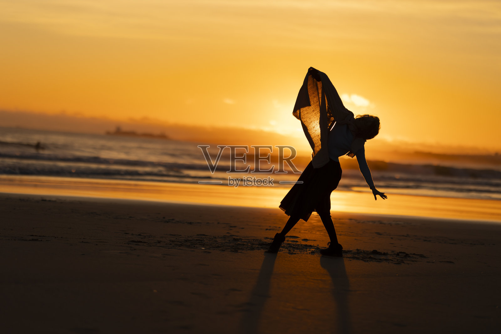 晚上，一个女人在海滩上跳舞照片摄影图片