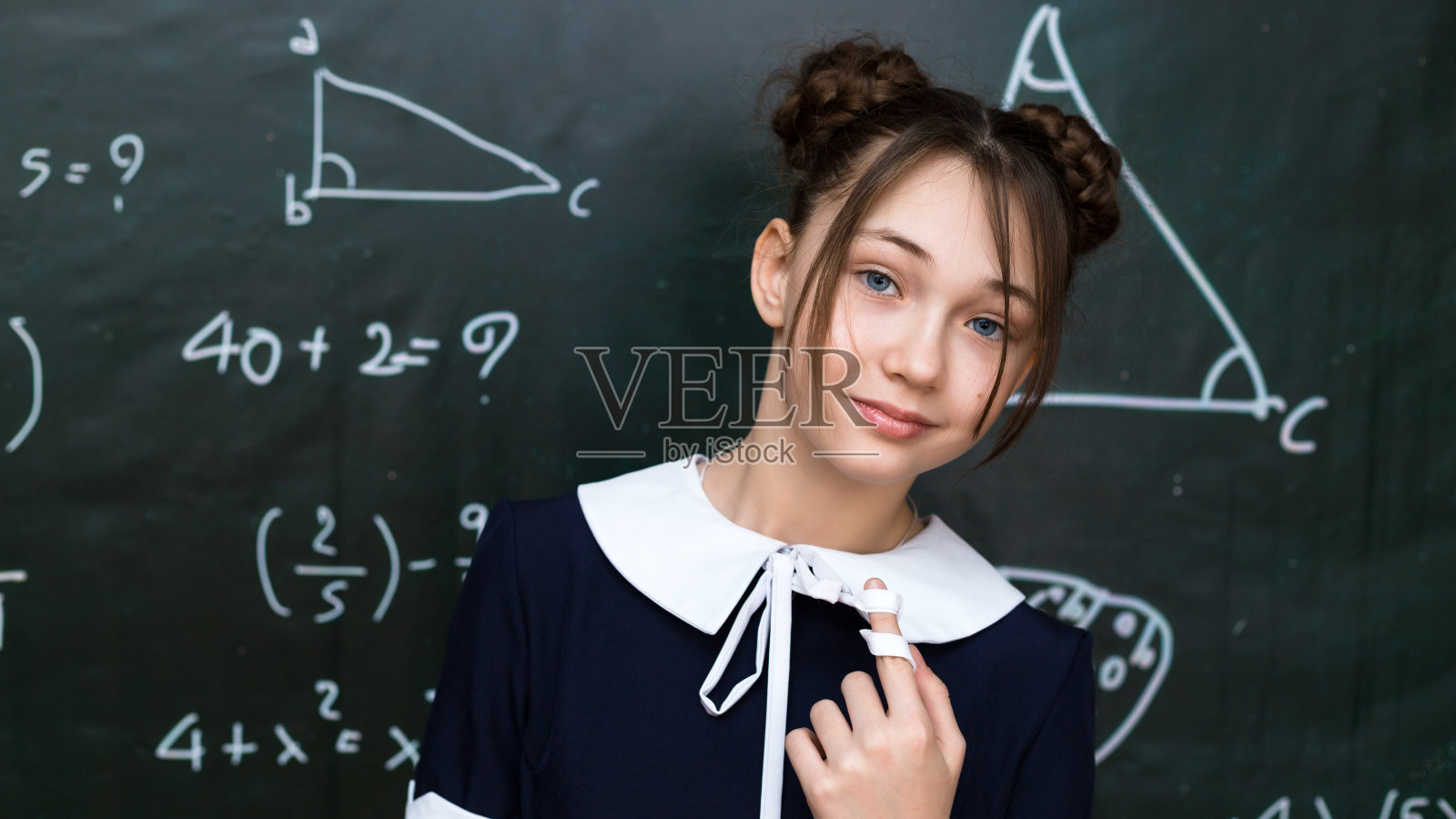 漂亮的棕色头发的十几岁的女学生靠近黑板，特写肖像照片摄影图片