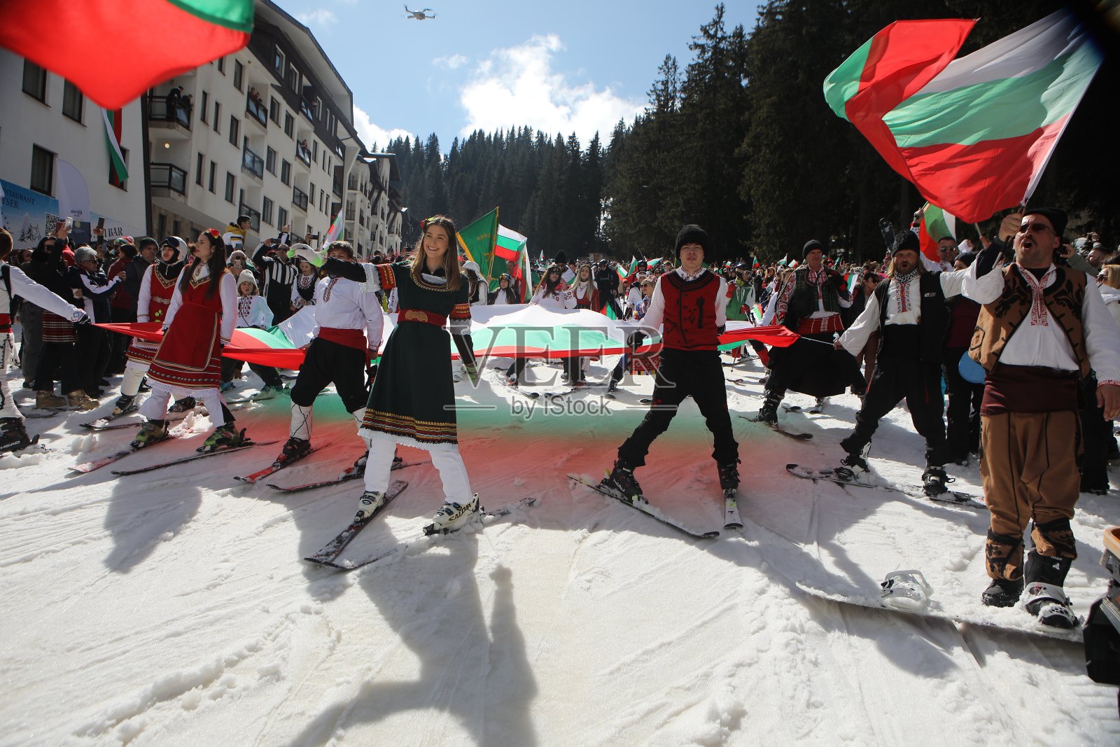 在保加利亚的潘波罗沃滑雪胜地，带着保加利亚国旗滑雪。人们穿着传统的保加利亚服装，举着保加利亚国旗在斯涅赞卡峰上进行滑雪游行照片摄影图片