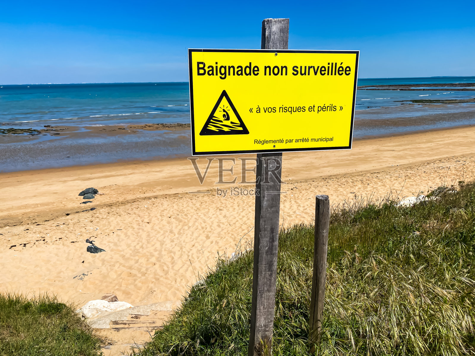 沙滩上的法语标志“无人监督游泳，风险自负”照片摄影图片
