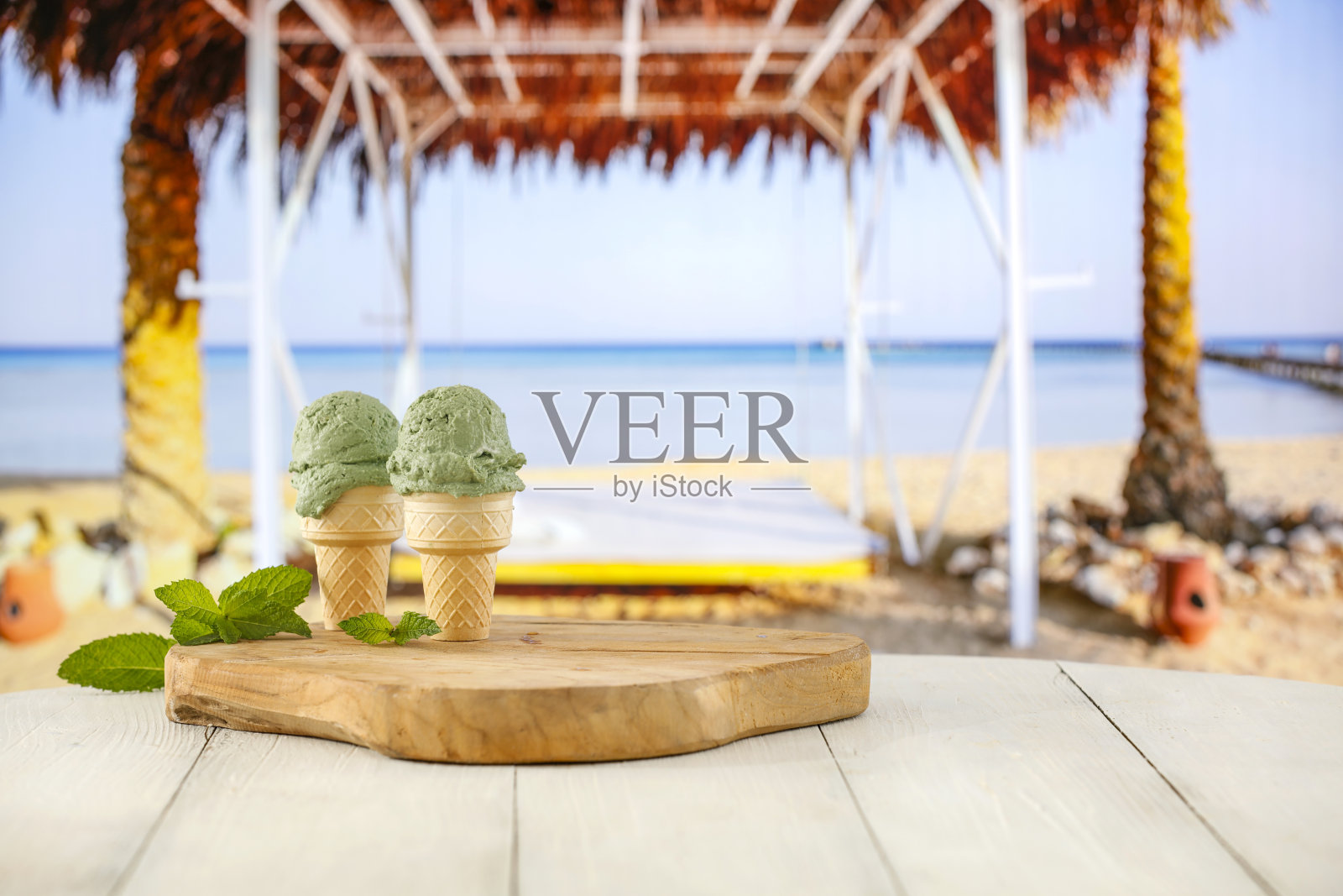 这张特写是在模糊的热带海滩背景下，桌子上的华夫蛋筒冰淇淋。照片摄影图片