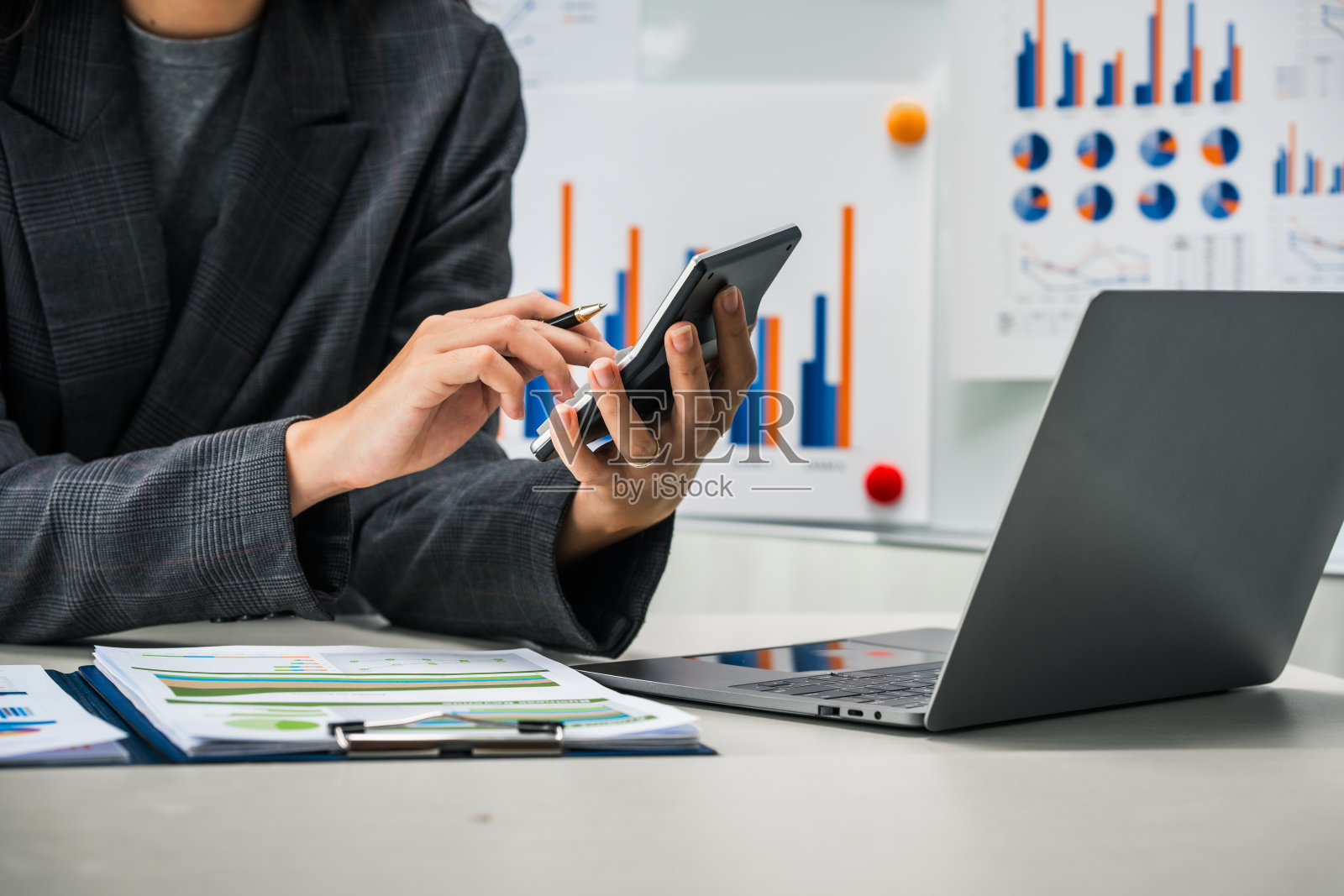 女商人在她的办公桌前勤奋地工作，审阅财务文件，分析投资数据。她确保财务计算和审计过程的准确性和效率。照片摄影图片