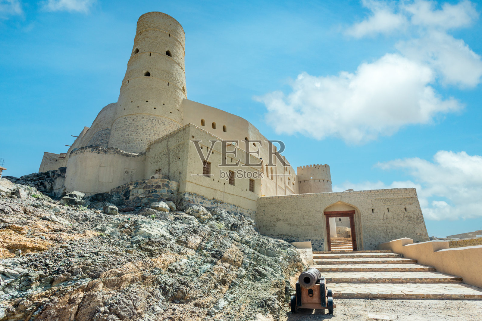 巴赫拉城堡的石墙和圆形塔楼，前景是旧炮，阿曼巴赫拉照片摄影图片