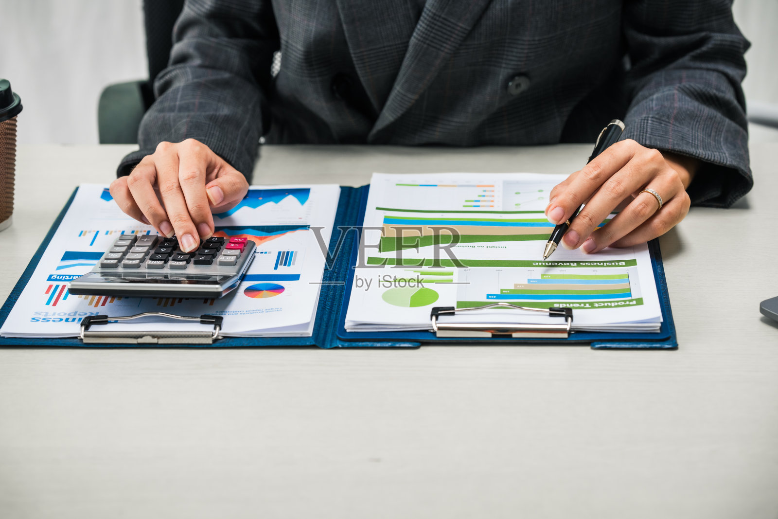 女商人在她的办公桌前勤奋地工作，审阅财务文件，分析投资数据。她确保财务计算和审计过程的准确性和效率。照片摄影图片