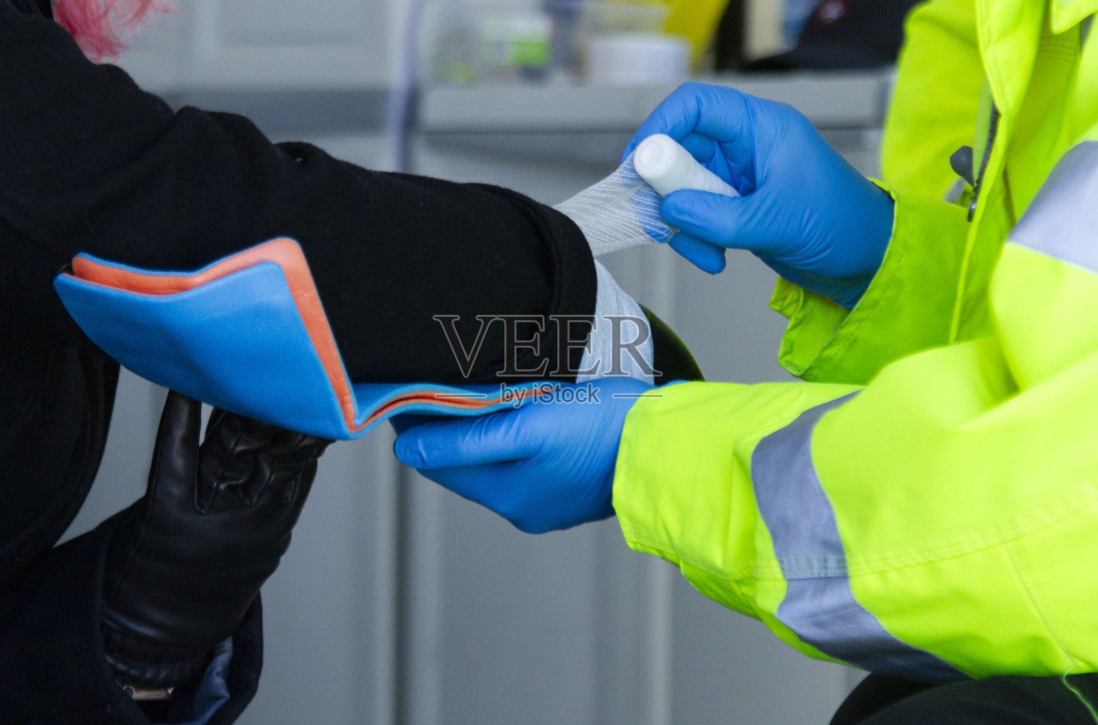 一名护理人员包扎病人的手臂，演示受伤肢体的急救程序。照片摄影图片