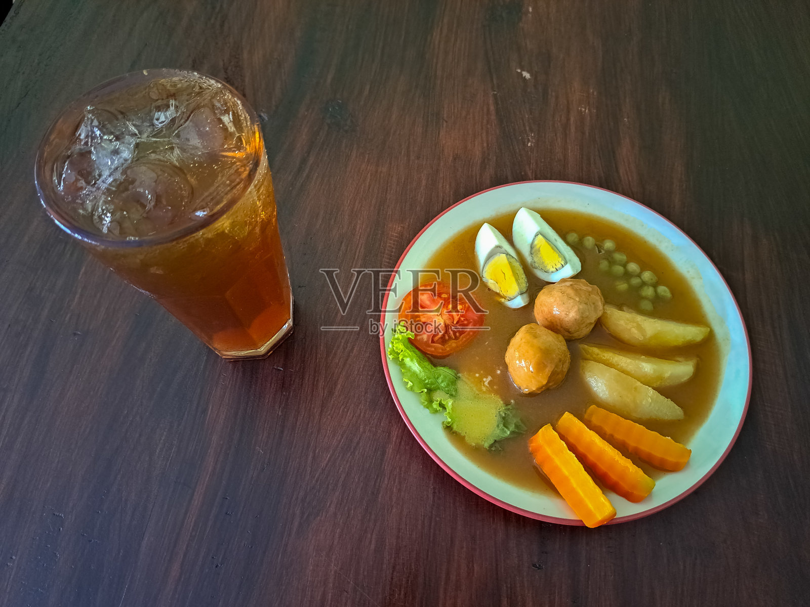 牛排是印度尼西亚的一种传统食物。配牛肉，土豆，煮蛋，西红柿，生菜，青豆和胡萝卜。冰鲜茶或加糖杯。食物和饮料菜单。照片摄影图片