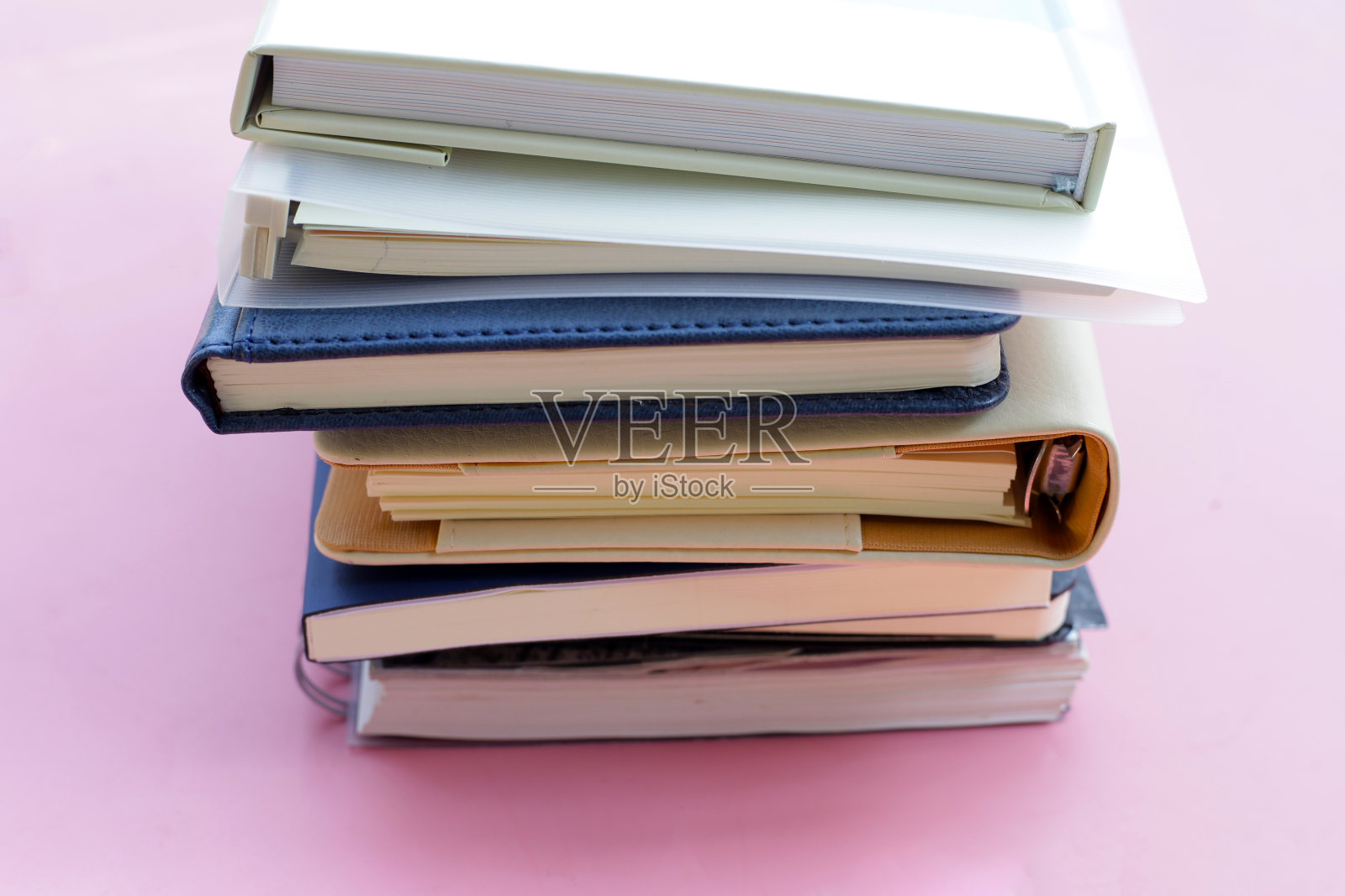 粉红色背景上的一叠笔记本。照片摄影图片