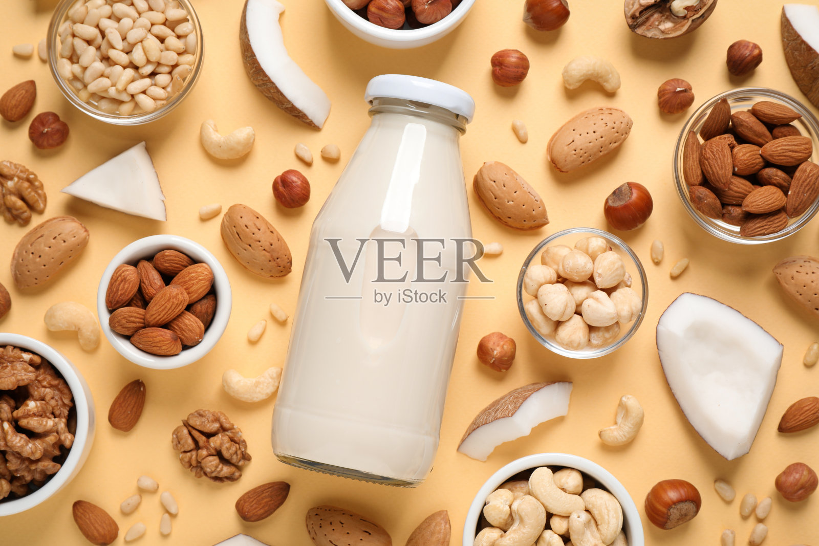 纯素牛奶和不同的坚果，米色背景，平铺照片摄影图片