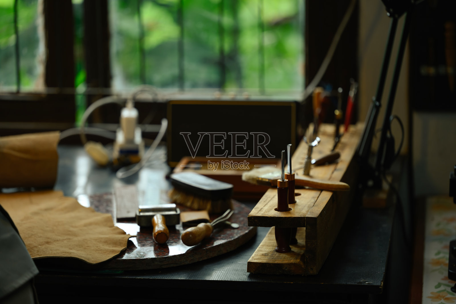 在当地的一个车间里，木桌上制作皮革制品的静物工具。鞋匠的工作场所照片摄影图片