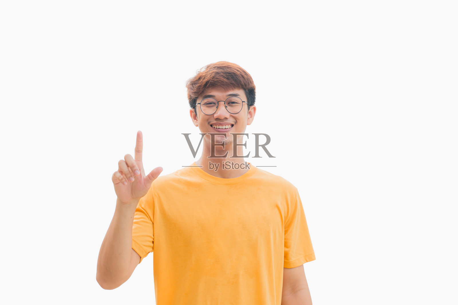 身穿黄色t恤的20多岁的亚洲青年正在触摸灰色背景中孤立的空白屏幕。照片摄影图片