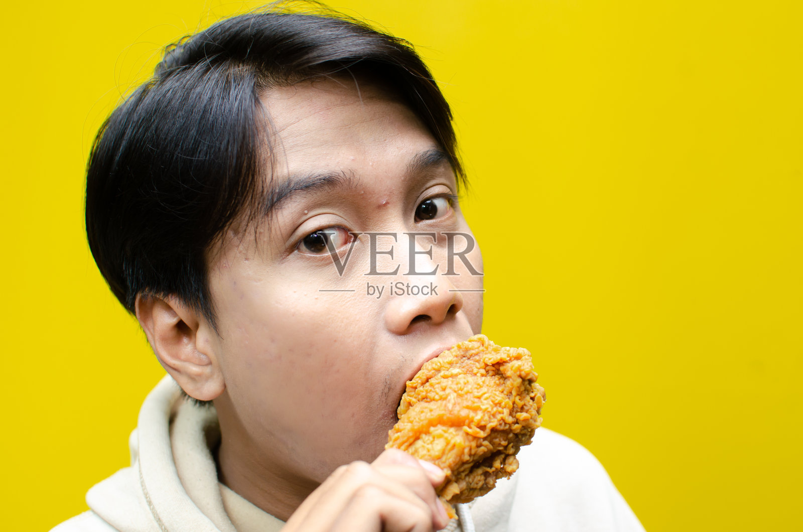 年轻的亚洲男子吃着炸鸡腿，脸上充满了享受的表情照片摄影图片