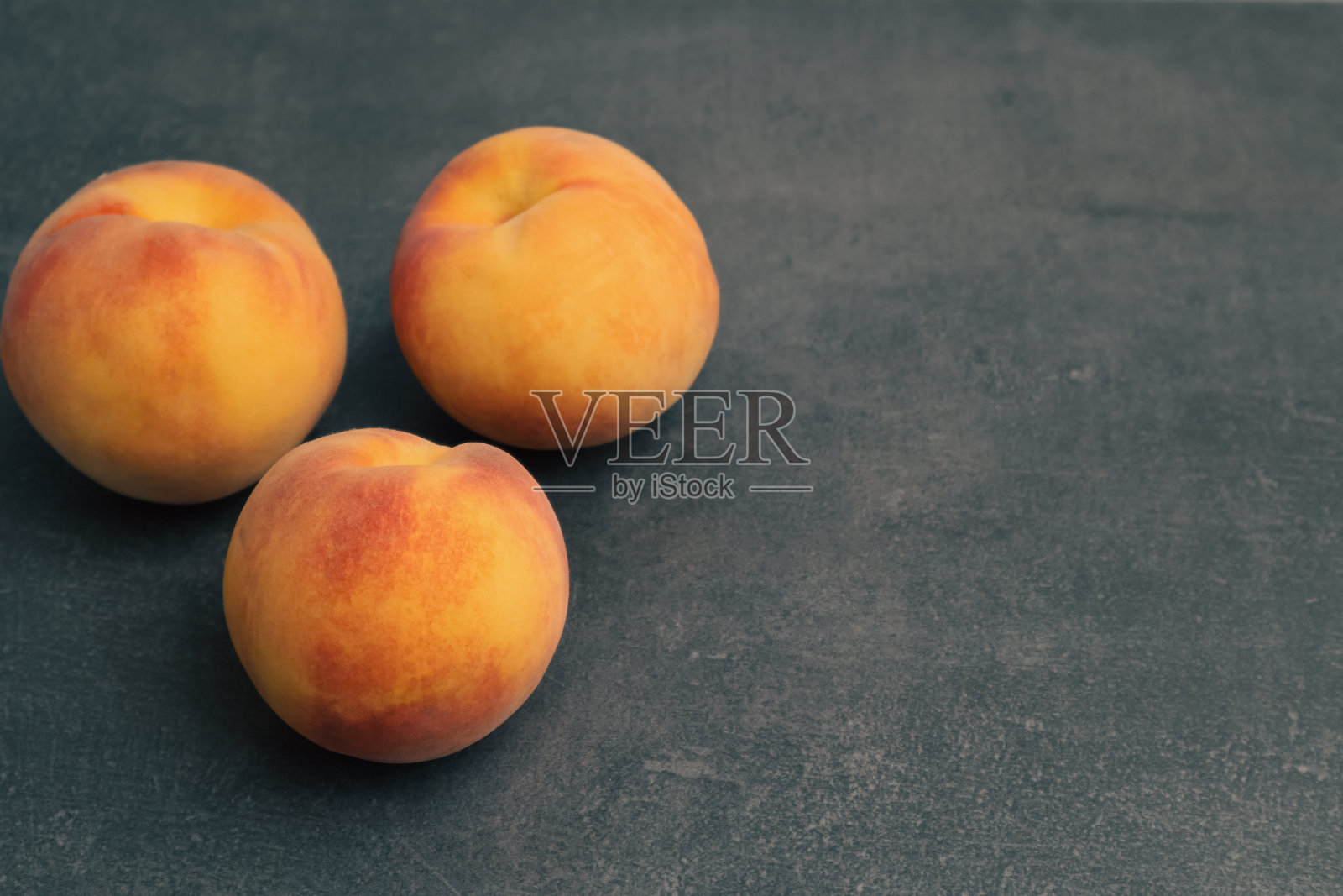 新鲜的桃子水果在黑色的石头背景。健康的生活方式，饮食理念。熟桃子在石头上。照片摄影图片