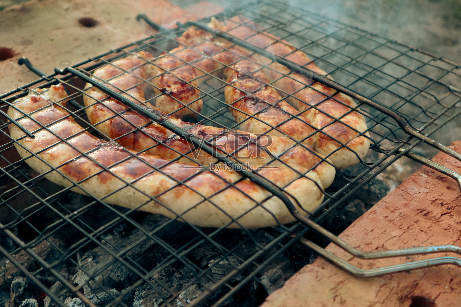 烤架上烤着火辣辣的香肠。在铸铁烤架上烤猪肉香肠照片摄影图片
