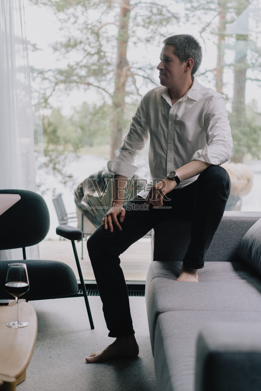 坐在沙发上，手里拿着手机或智能手机的男人。照片摄影图片