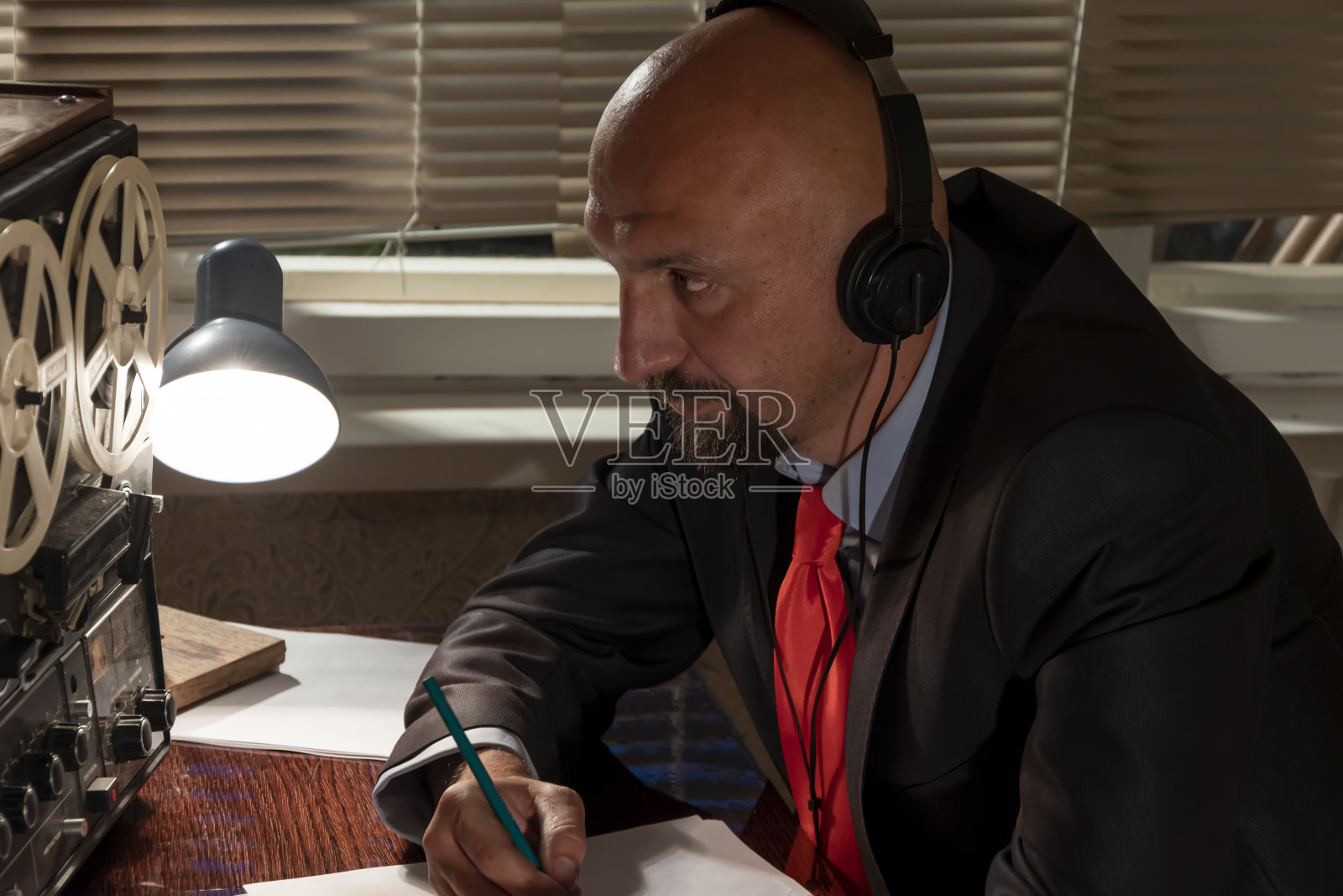 秃头男人戴着耳机听音乐，听录音谈话，监视和控制人，平均计划照片摄影图片