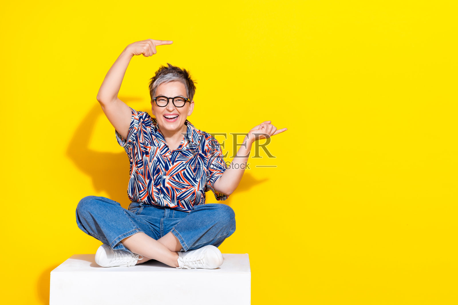 漂亮的退休妇女的全尺寸照片，坐在立方体点空的空间穿时髦的彩色服装孤立在黄色的背景照片摄影图片