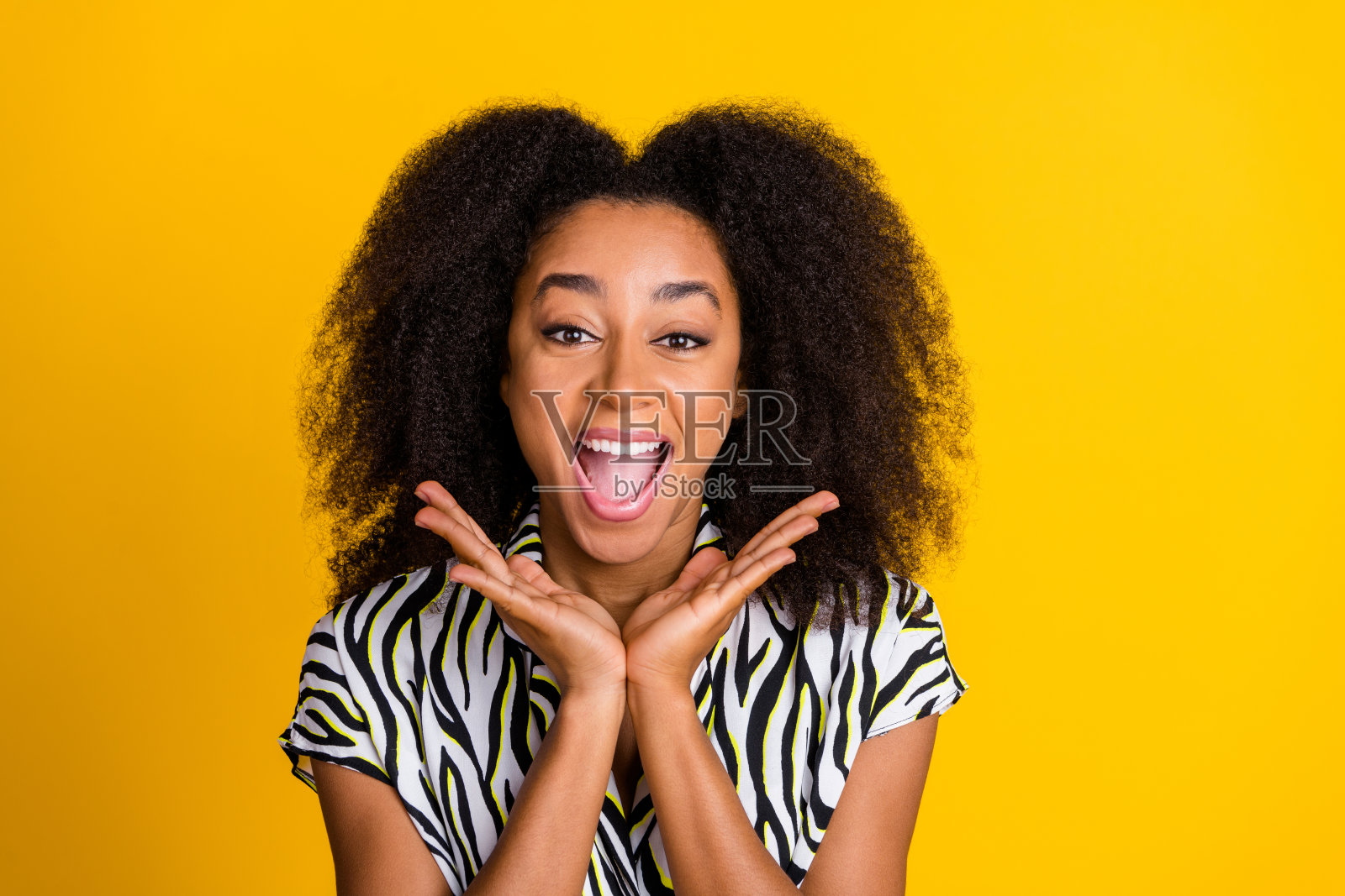年轻女士的肖像，穿着漂亮的卷发衬衫，触摸脸颊的反应，看着她的惊讶孤立在黄色的背景照片摄影图片
