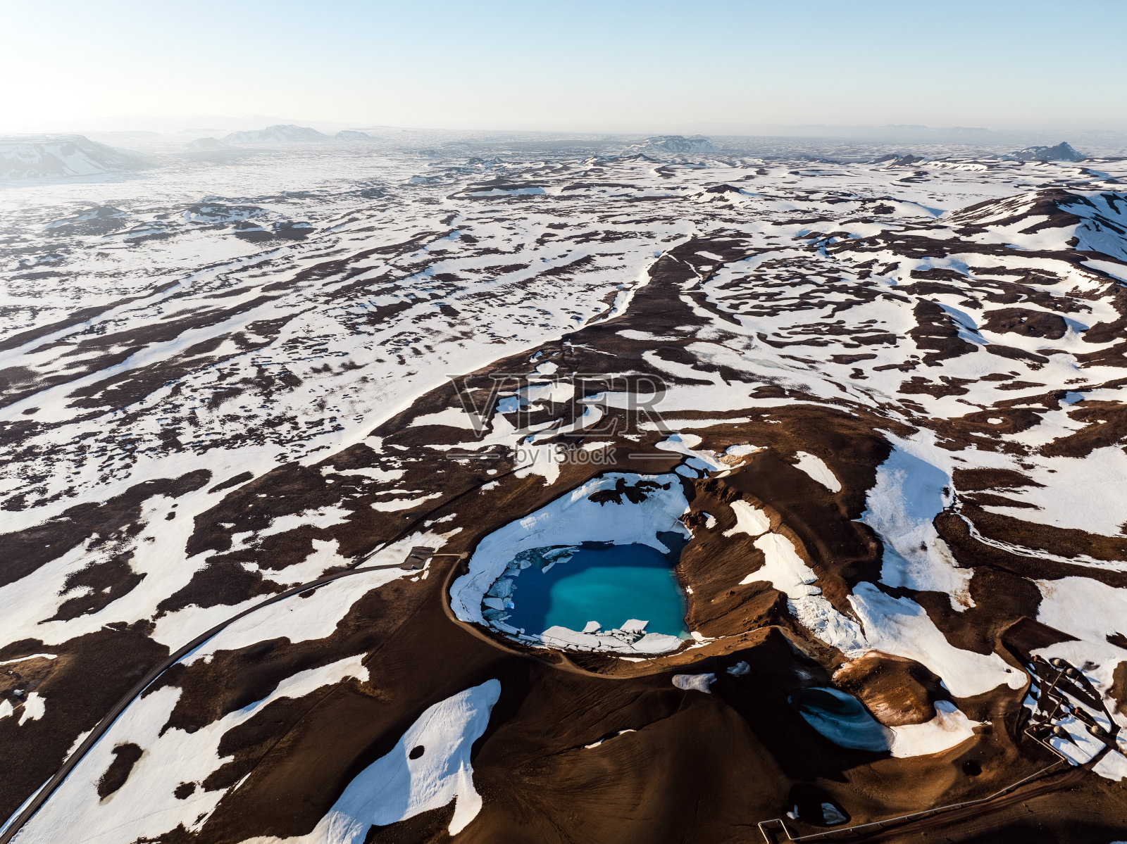 从空中俯瞰，克拉夫拉维提陨石坑令人惊叹的鸟瞰图。这个美丽的火山口充满了蓝色的水，周围是地热区和五颜六色的山脉。冰岛。照片摄影图片