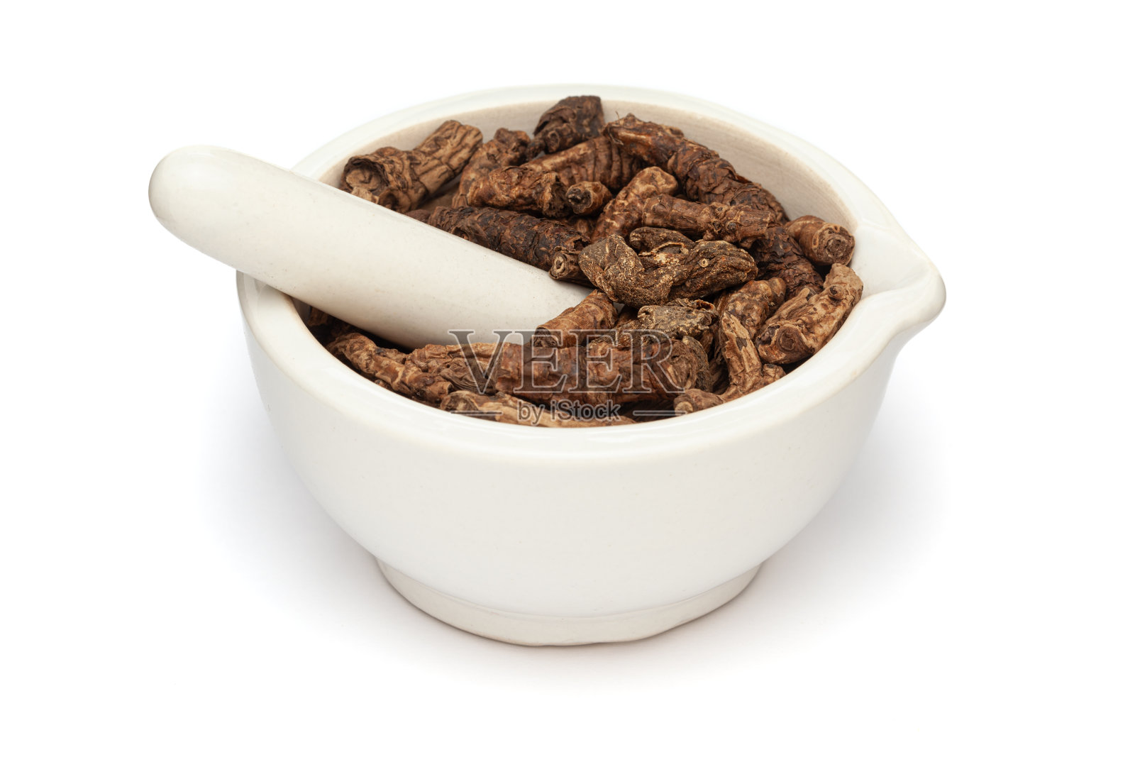 干燥有机海菜或库奇(Picrorhiza kurroa)根的特写，在白色的陶瓷砂浆和杵中，隔离在白色的背景上。照片摄影图片