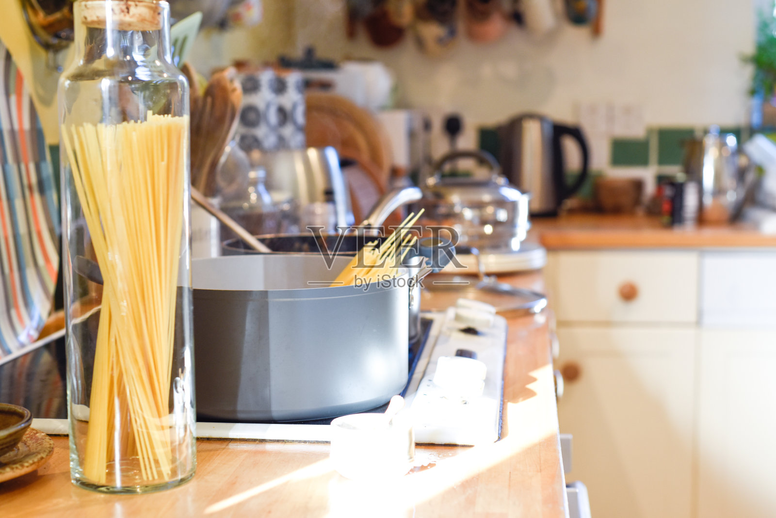 烹饪意大利面在家庭厨房里，锅里有煮意大利面的水和厨房柜台上的原料照片摄影图片