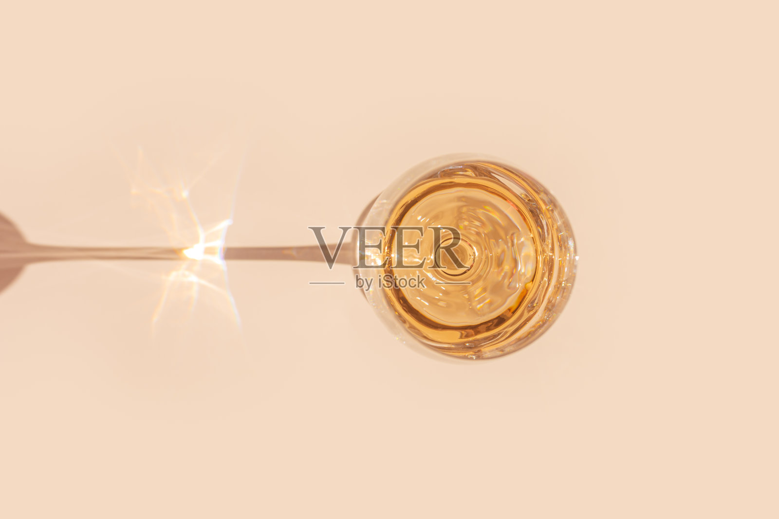 白葡萄酒装在晶莹透明的玻璃中，在阳光下带有阴影和眩光，浅桃色背景，创意夏日休息酒饮的极简概念，复制空间，上面，柔和的颜色照片摄影图片