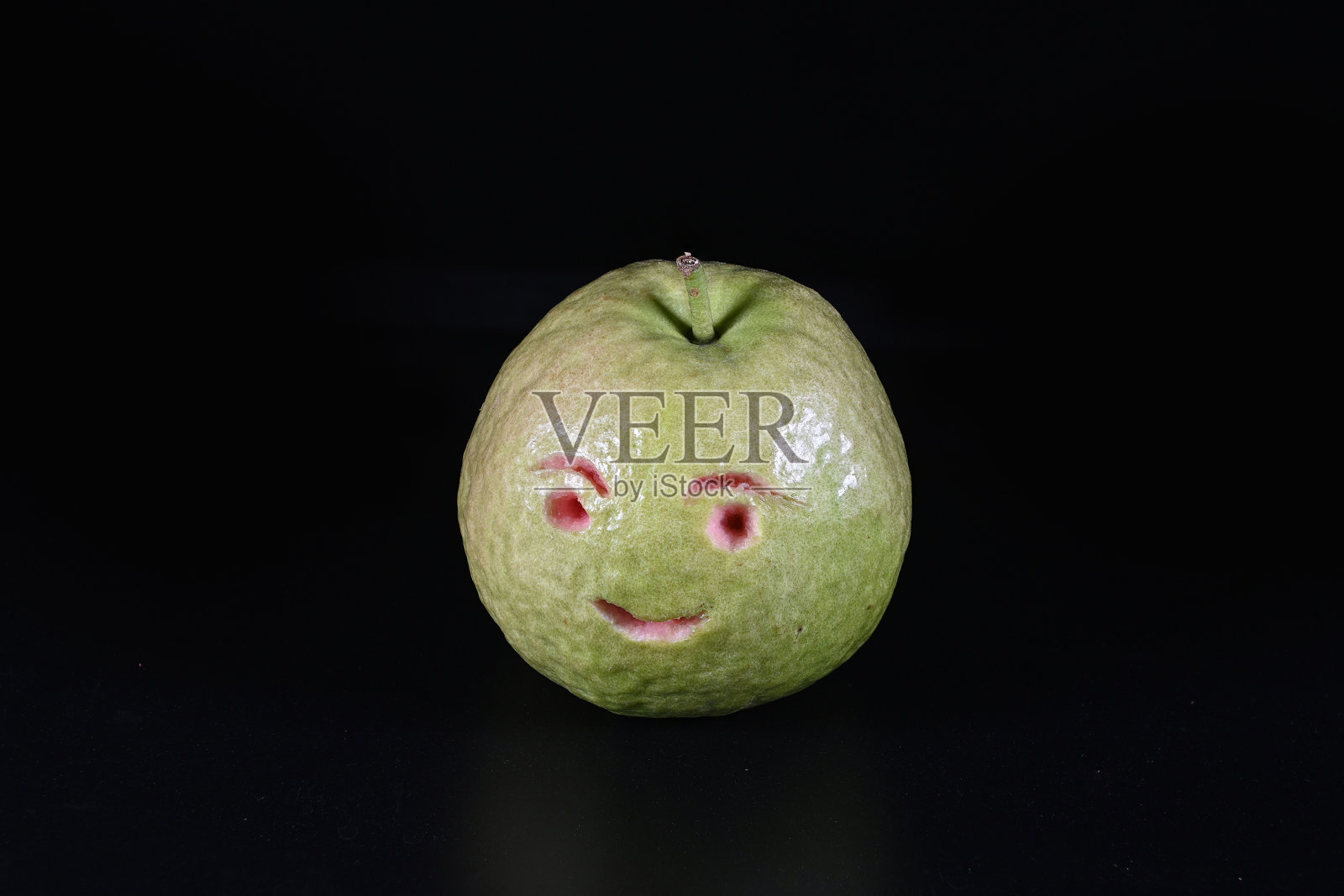 新鲜番石榴与雕刻的笑脸在一个黑色的背景照片摄影图片